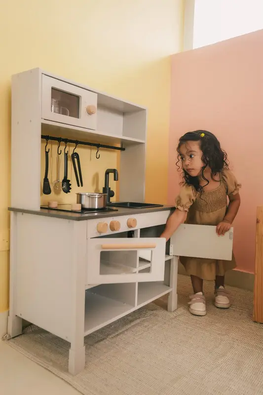 Niña explorando la cocina de juego del aula