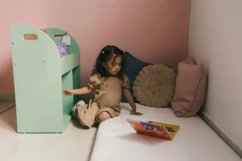 Niña eligiendo un libro en el rincón de lectura