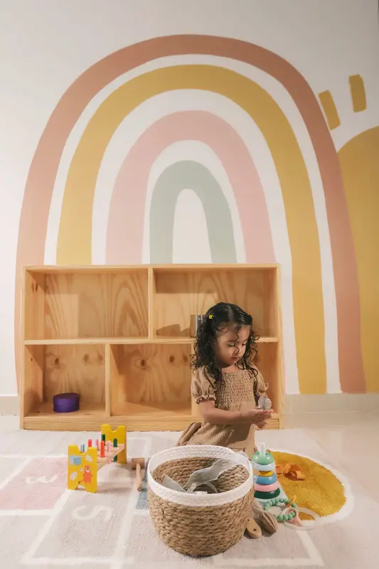 Niña jugando frente al mural de arcoíris del centro