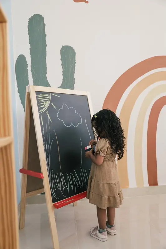 Niña dibujando con tizas en la pizarra